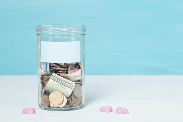 Coins and banknotes in glass money jar, financial donations, charity concept